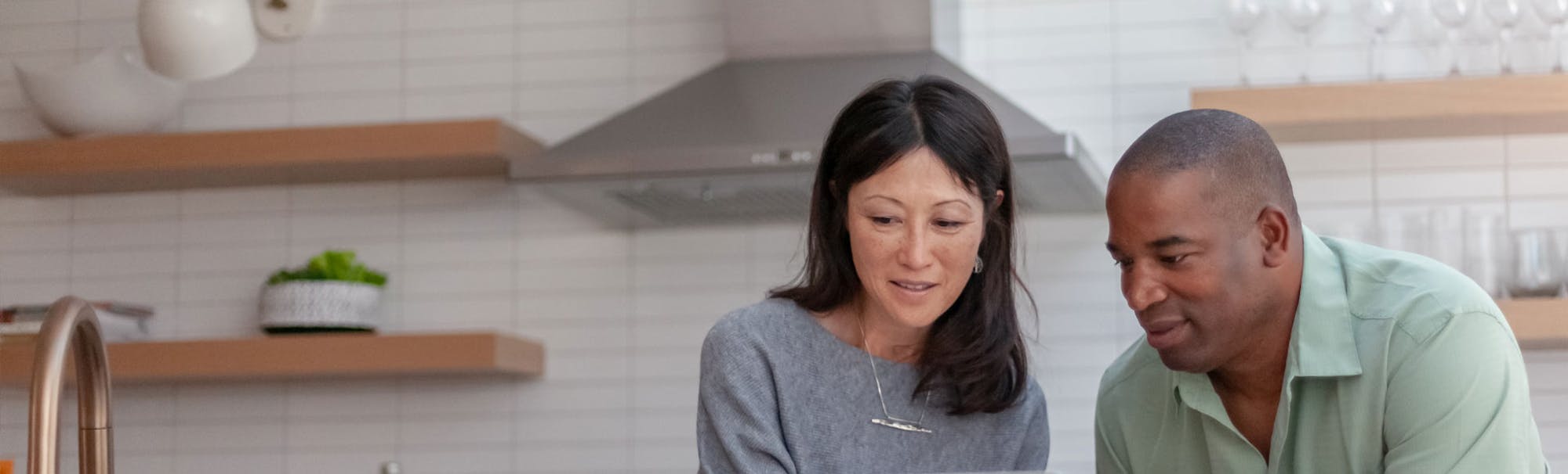 Couple in kitchen looking at BankVic offset home loan on laptop