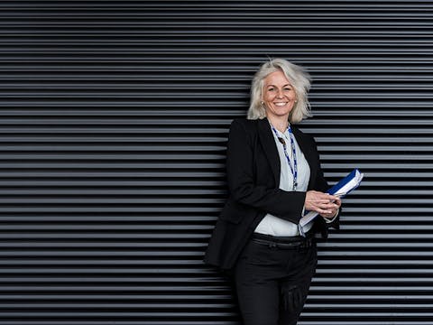 A lady standing against a solid dark background