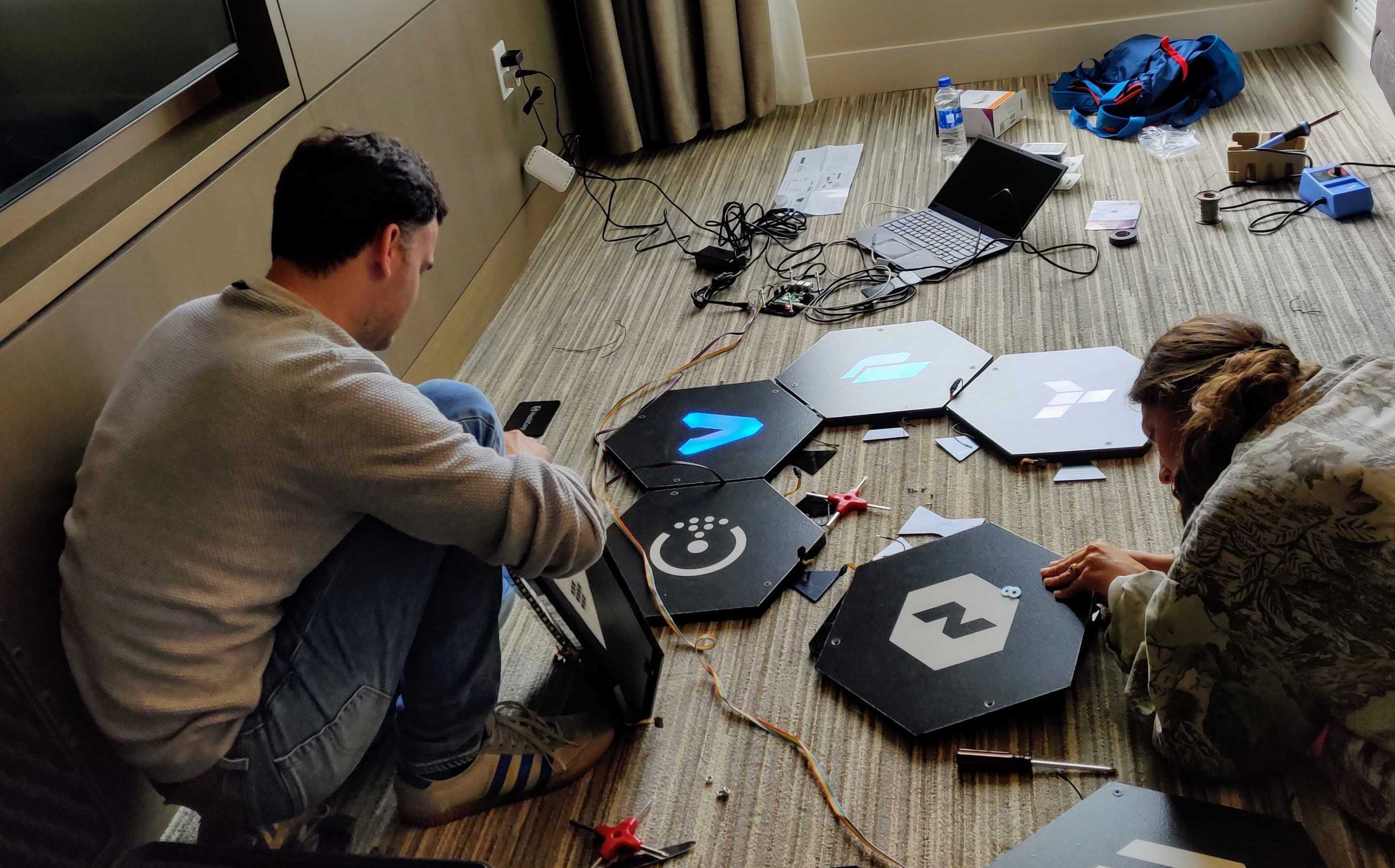 Two engineers soldering hexagonal dance tiles