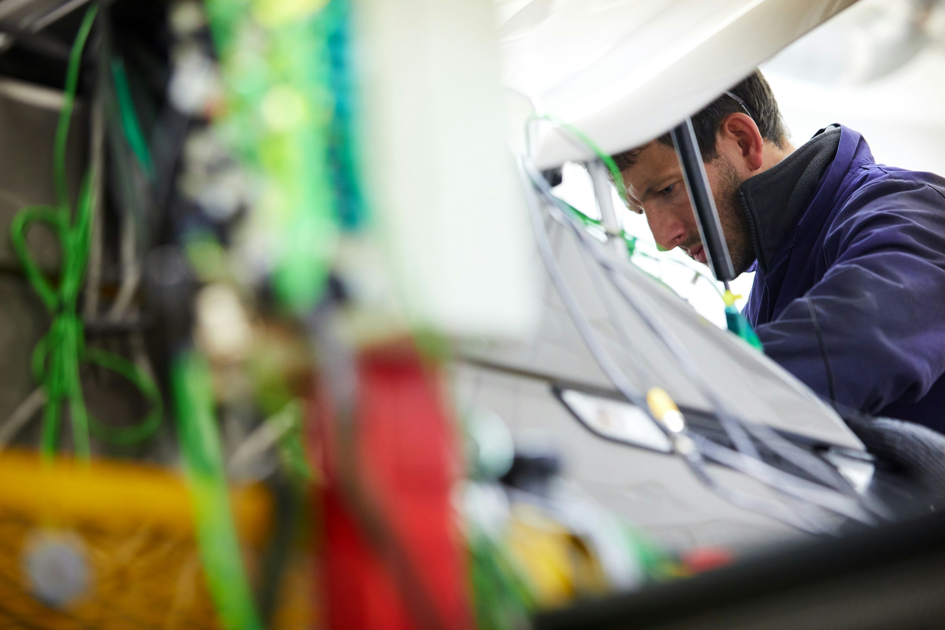 Engineer working in vehicle engine bay with dynamometer cabling in the foreground