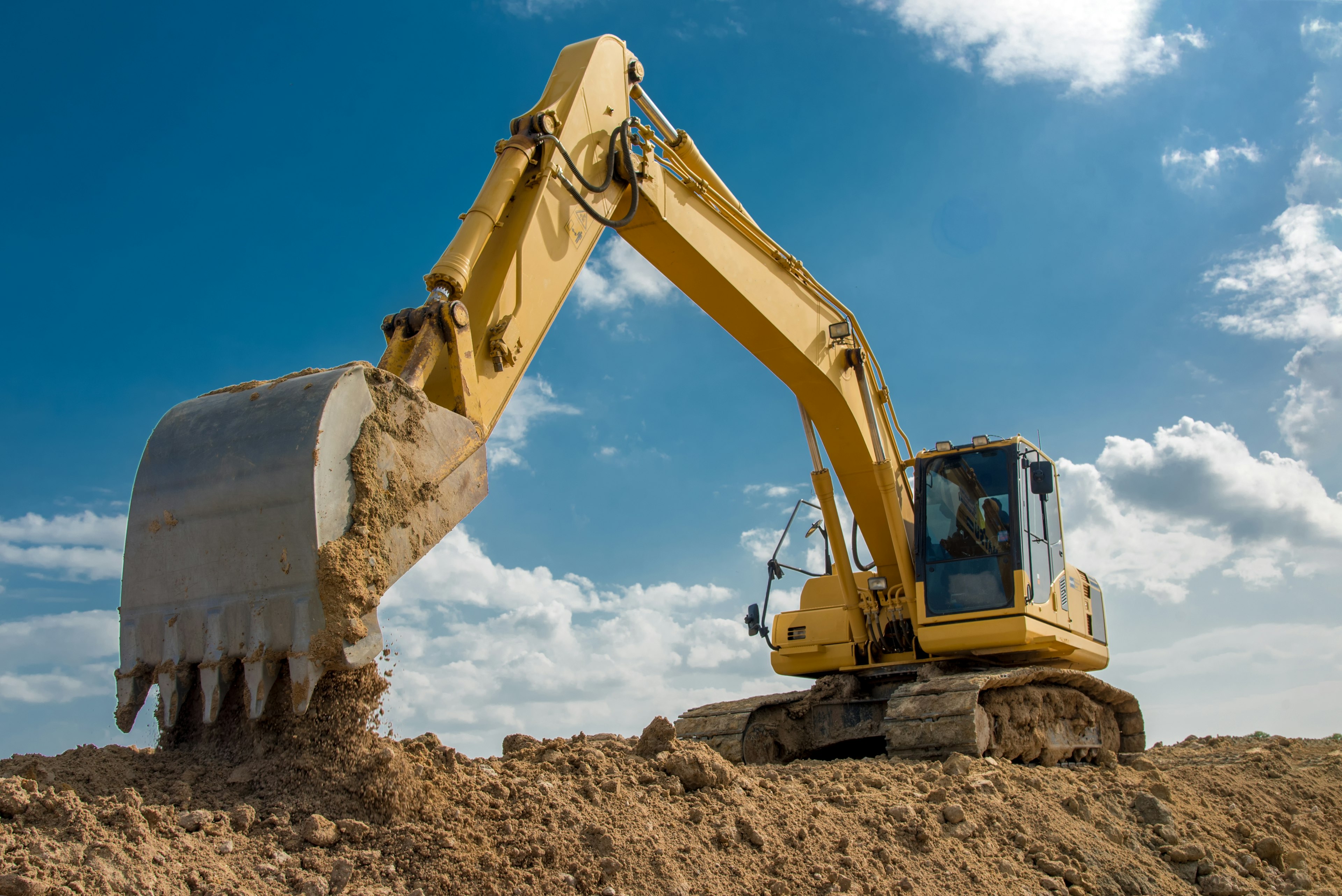 Excavator dropping soil on construction site