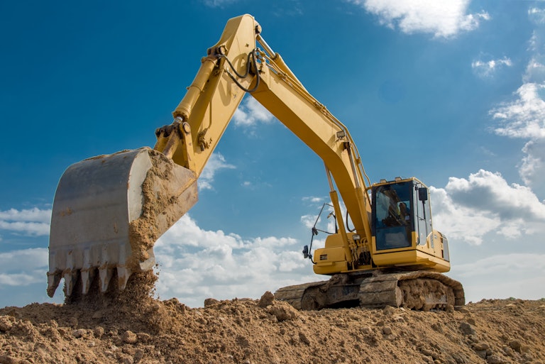 Excavator dropping soil on construction site