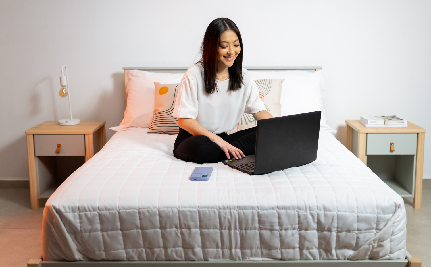 Mulher usando notebook sentada na cama 
