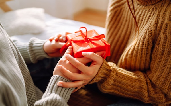 Um homem entregando uma caixa de presente vermelha para uma mulher