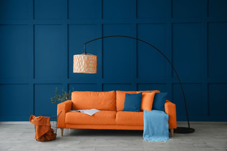 sala com sofá laranja e parede azul escura
