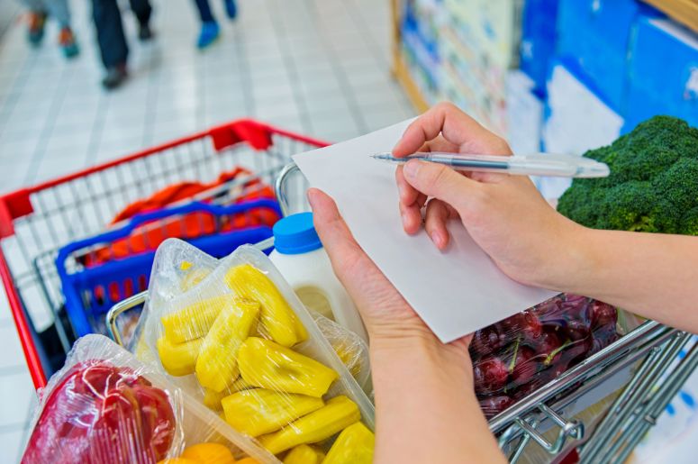 mulher com lista e carrinho de compras