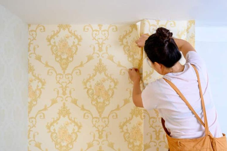 mulher colocando o papel de parede