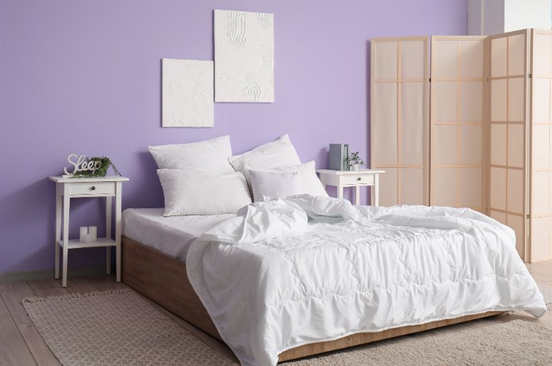 quarto com parede lilás e móveis branco