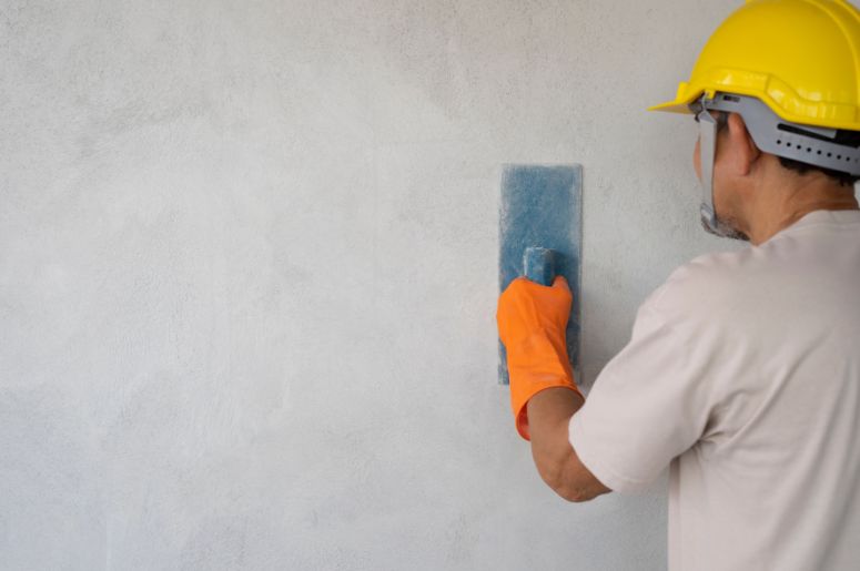 Homem aplicando cimento na parede 