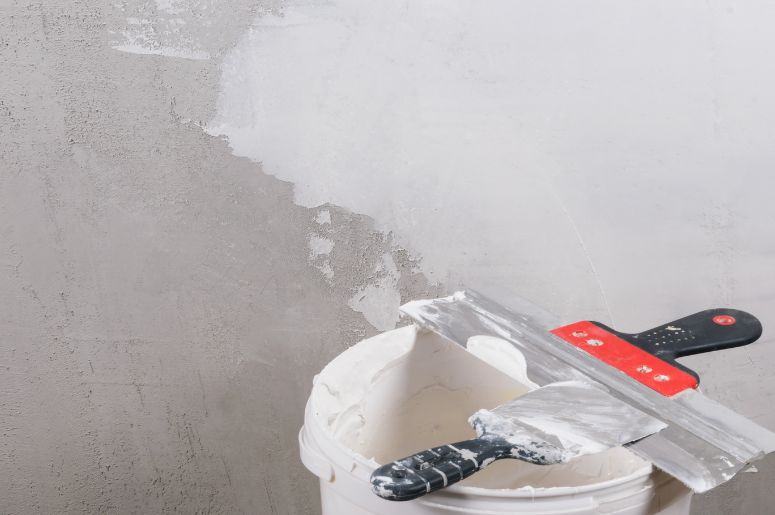 Parede com massa corrida e balde sujo com massa corrida