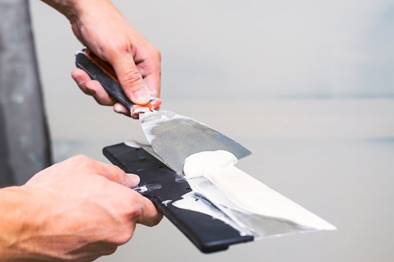 Homem aplicando a primeira demão de massa corrida