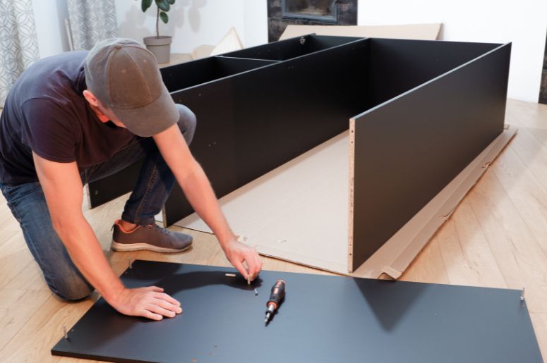 Homem montando guarda roupa deitado