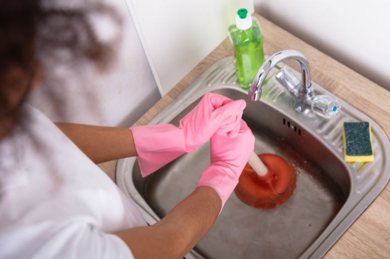 Mulher com desentupidor na pia