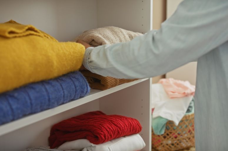 Mulher guardando roupas no guarda-roupa