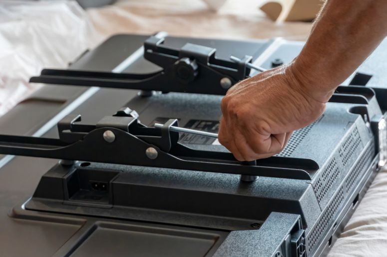 Homem colocando os suportes na TV