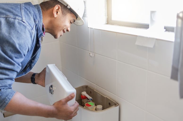 Encanador consertando vaso sanitário 