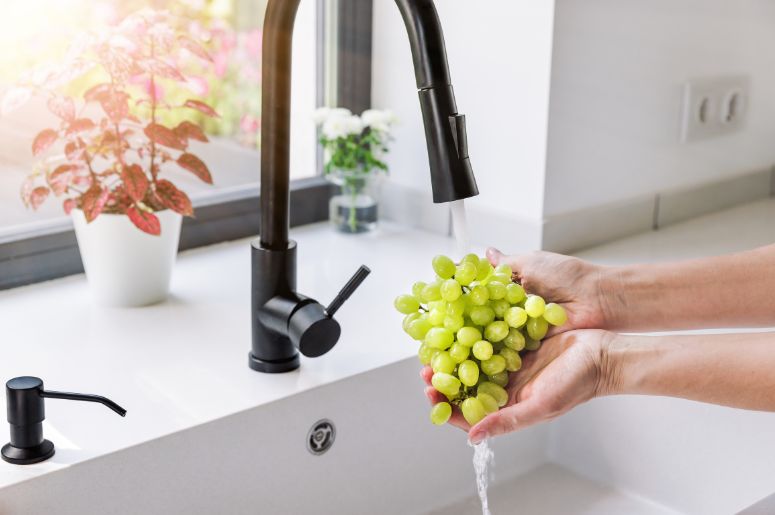 Mulher lavando uvas na torneira
