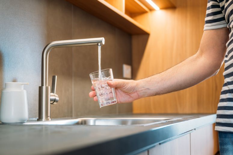 Mulher enchendo o copo com &aacute;gua da torneira