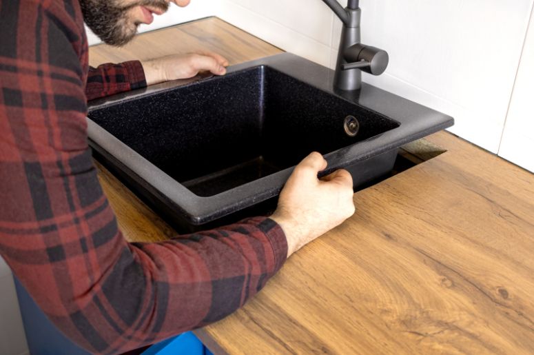 Homem instalando pia de cozinha