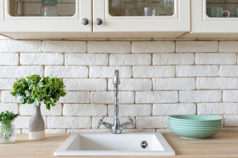 Cozinha decorada com tijolos brancos e pia branca