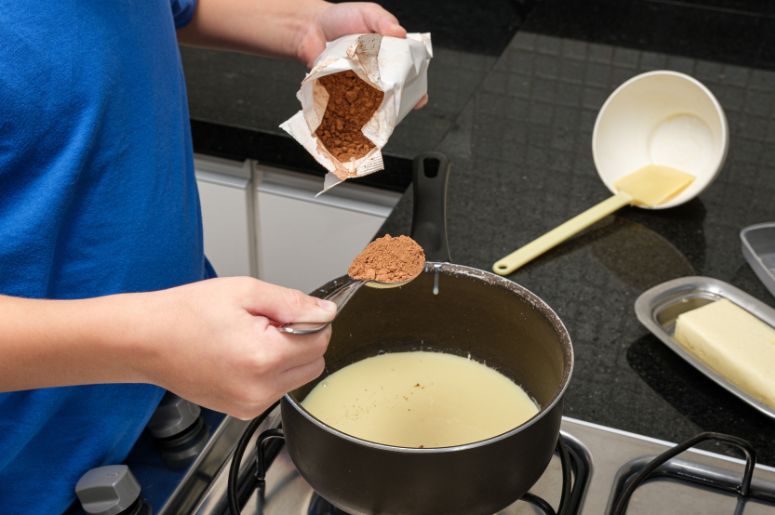 Pessoa adicionando os ingredientes do brigadeiro em uma panela 