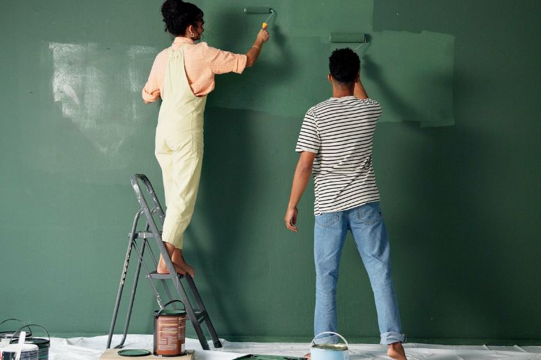 Casal pintando parede com a cor verde