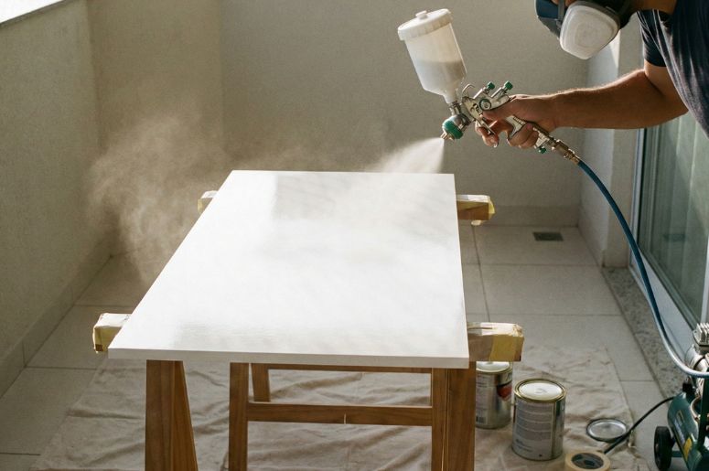 Pessoa aplicando laca em m&oacute;vel