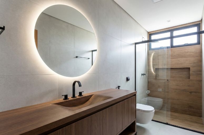 Banheiro com móveis marrom e espelho com LED