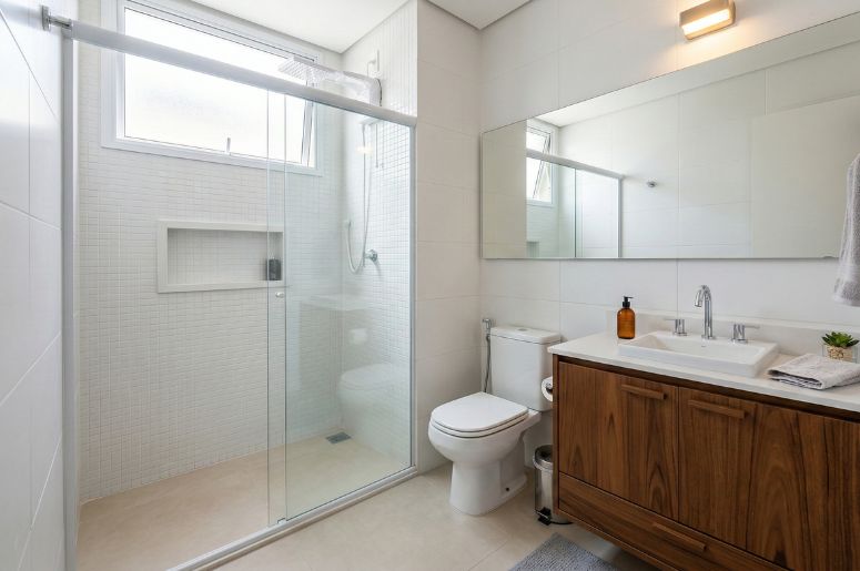 Banheiro com box e gabinete de madeira