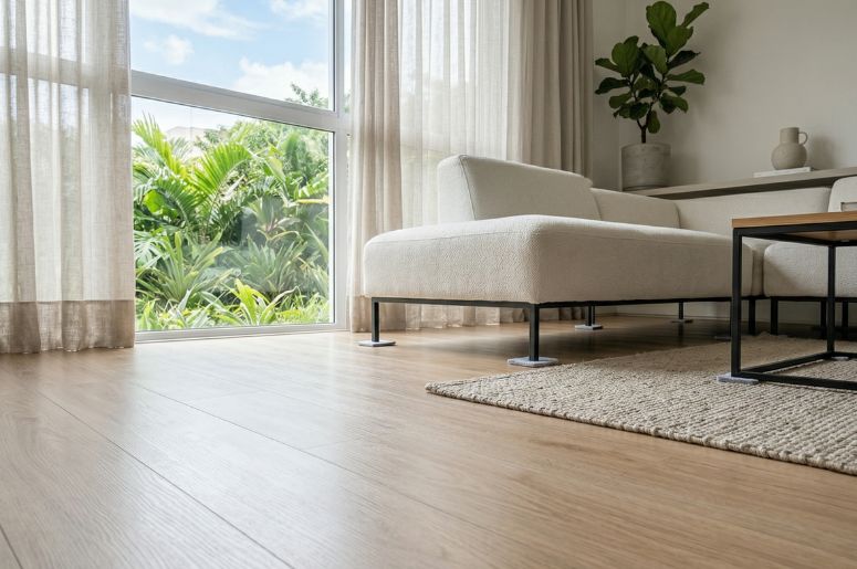 Sala com sofá off-white, mesa de centro industrial e piso laminado