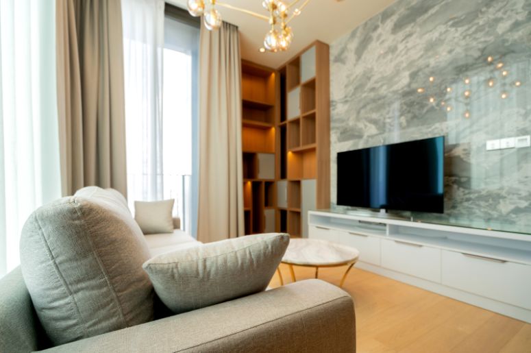 ack para sala pequena moderna com móvel branco para TV, painel marmorizado, sofá cinza, mesa de centro e estante de madeira iluminada