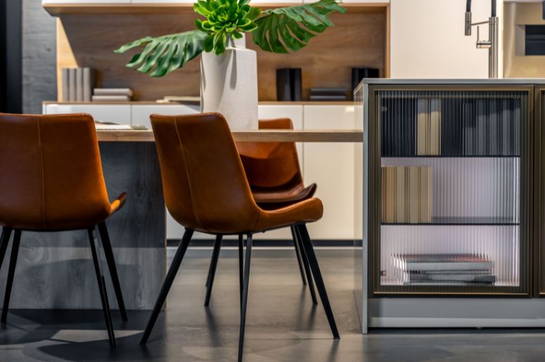 Cadeiras estofadas em couro marrom ao redor de uma mesa de madeira em sala de jantar moderna, destacando diferentes modelos de cadeiras para compor ambientes elegantes e funcionais