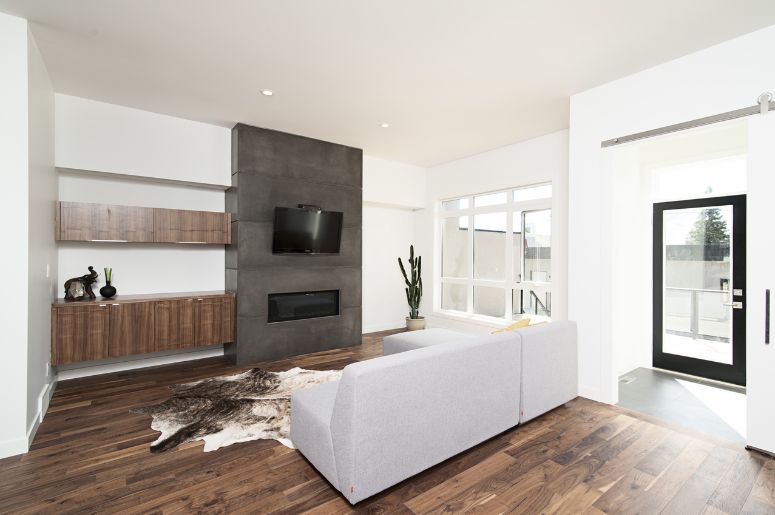 Sala de estar com sofá cinza, rack suspenso de madeira e painel com TV e lareira