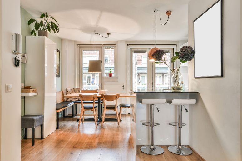 Cozinha e sala de jantar integradas em conceito aberto, com bancada, banquetas e mesa de madeira