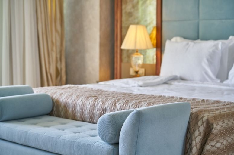 Quarto moderno com cama estofada, banco aos pés e decoração em tons neutros e aconchegantes