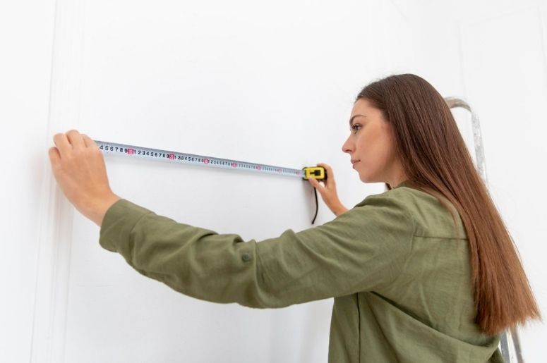 Mulher medindo uma parede com fita métrica