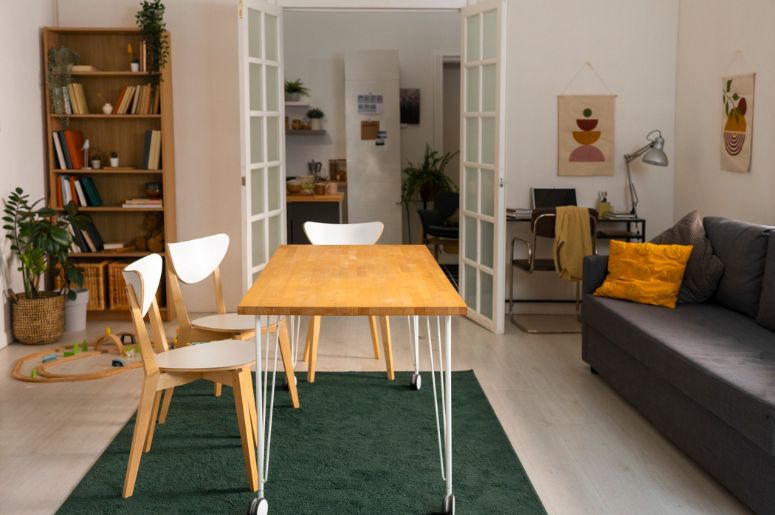Sala integrada de apartamento com mesa de jantar, sofá, estante e home office ao fundo