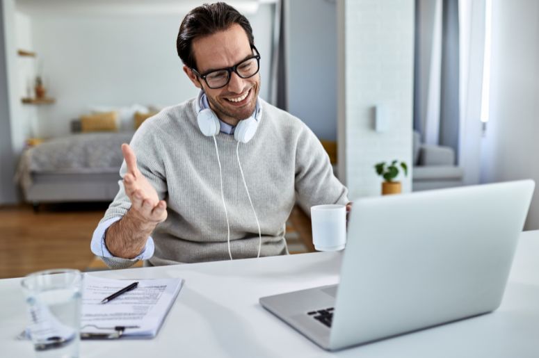 Homem trabalhando em home office com notebook, fones de ouvido e mesa organizada