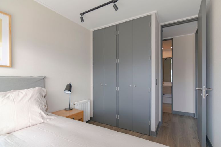 Quarto moderno com cama, mesa de cabeceira e guarda-roupa cinza planejado com portas de abrir