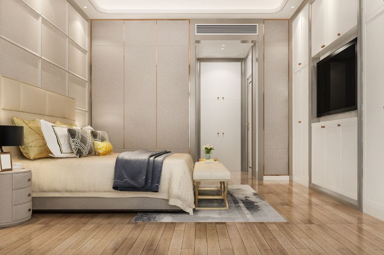 Quarto planejado em tons claros, com cama de casal, cabeceira estofada, criados-mudos, armários embutidos e painel com televisão na parede