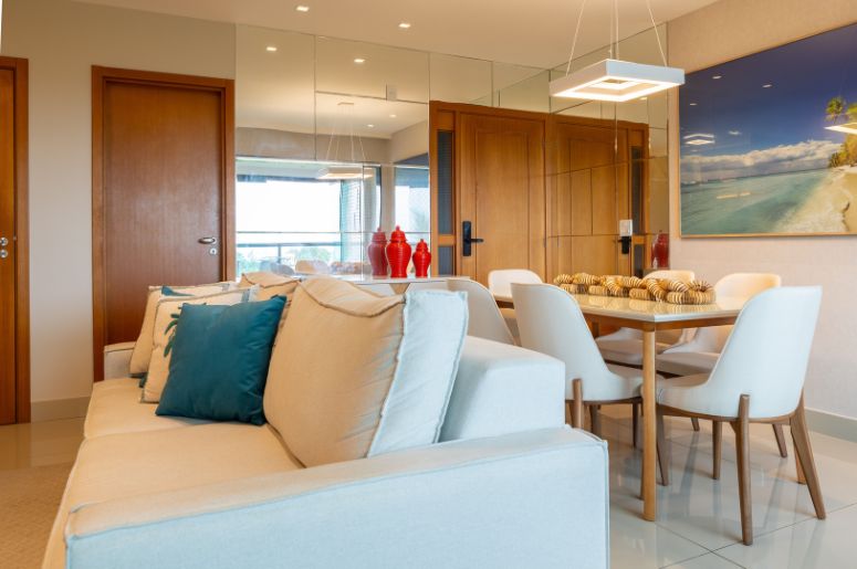 Sala de estar integrada à sala de jantar, com sofá claro, mesa retangular e decoração em tons neutros