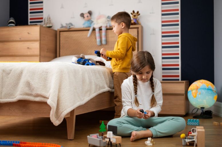 Quarto infantil com duas crianças brincando, cama de madeira, cômoda, brinquedos e decoração colorida