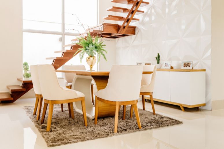 Mesa de jantar de madeira com cadeiras estofadas bege em sala integrada