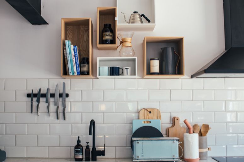 Cozinha com nichos aéreos decorativos, azulejos de metrô brancos e barra magnética de facas