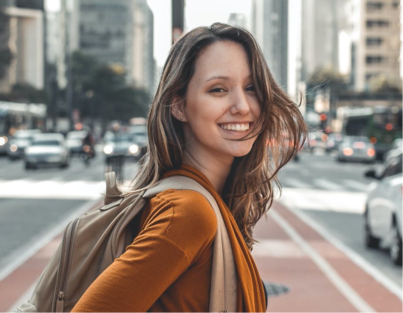 Woman smiling in the middle of a busy street.