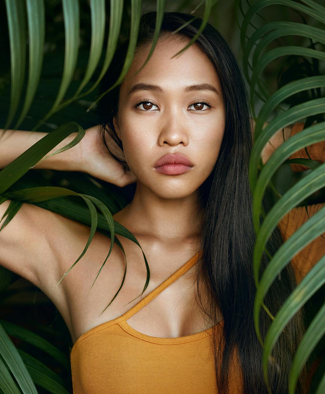 Beautiful Woman with big lips, standing behind leaves from a tree in Brooklyn.