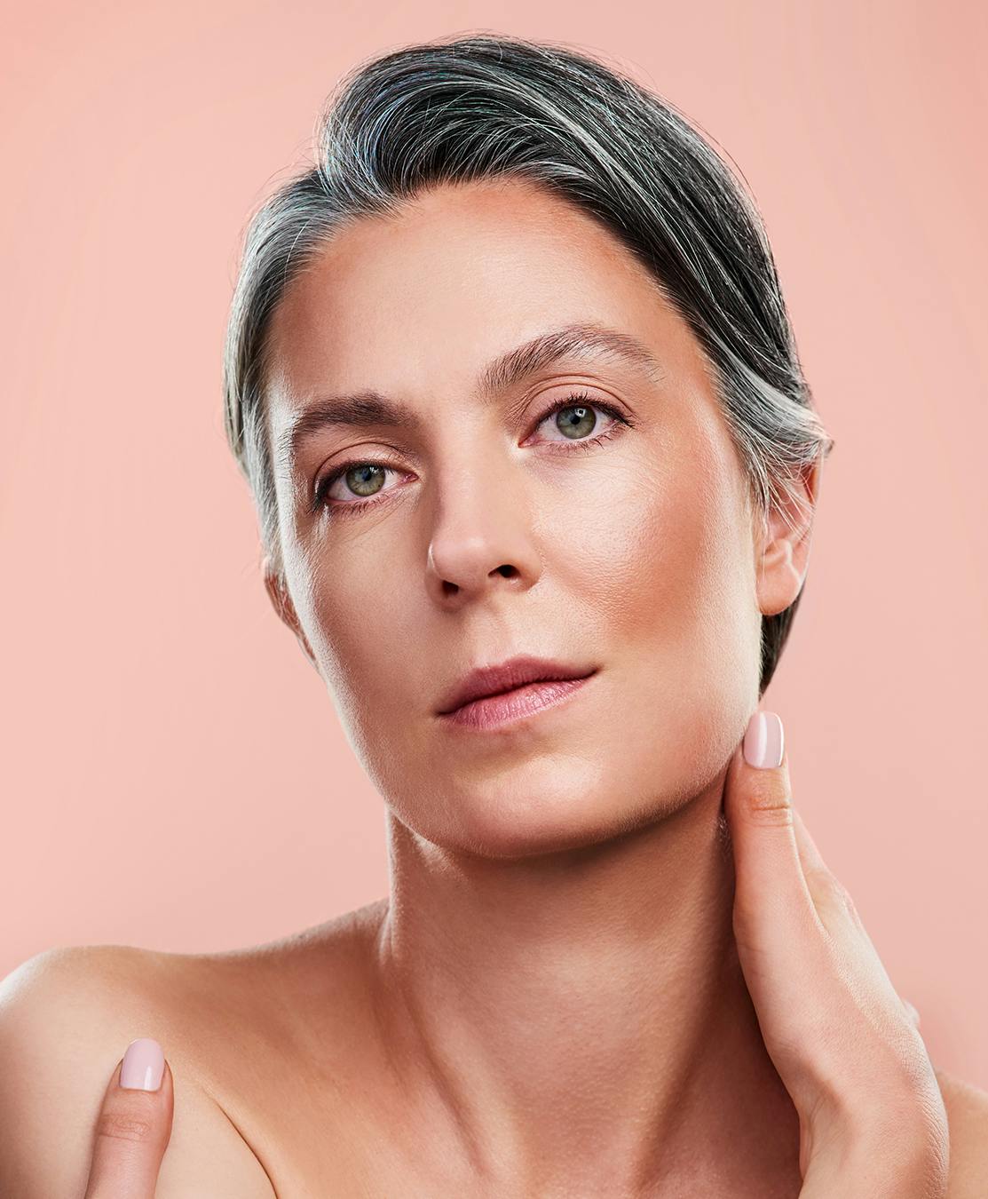 Woman with grey hair and a peach background.