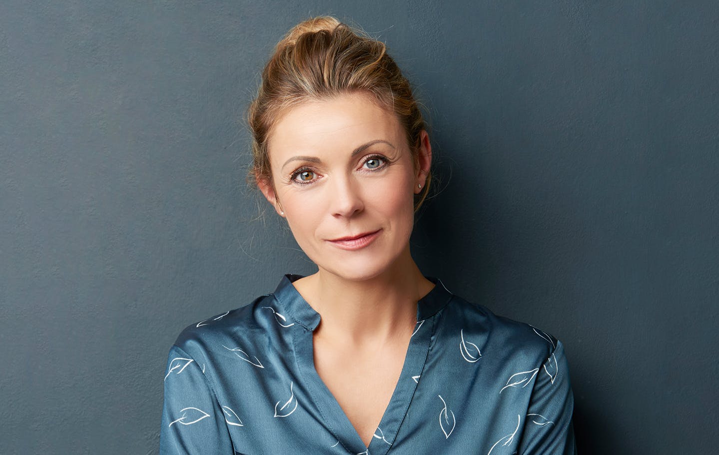 Woman posing in front of blue background.
