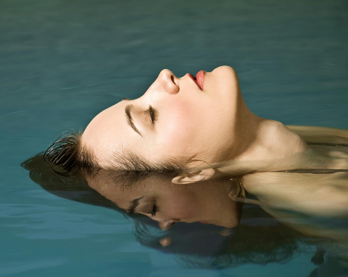Close up on woman's face as she floats in water. 