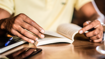 Hands flipping through a book at a table